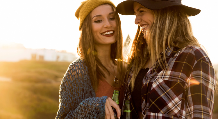2 mejores amigas están juntas, sonriendo y disfrutando de momentos juntas, tomando una cerveza, compartiendo secretos.