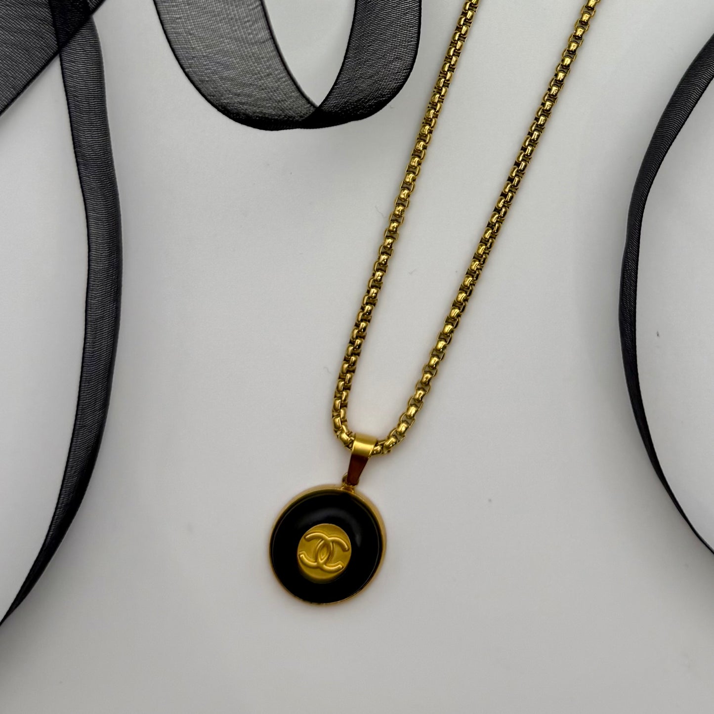 Joya artesanal sostenible con botón CHANEL reciclado.
