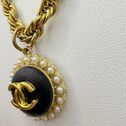 Detalle del botón recuperado de marca de lujo, negro y dorado, en collar artesanal DEMETRA hecho a mano por EOS UPCYCLING