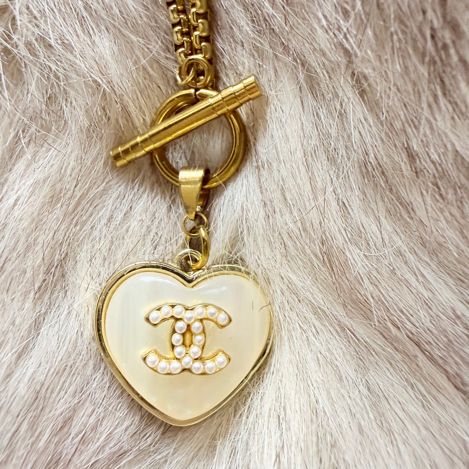 Detalle del botón de marca de lujo recuperado y transformado en collar artesanal ORITIA hecho a mano por EOS UPCYCLING