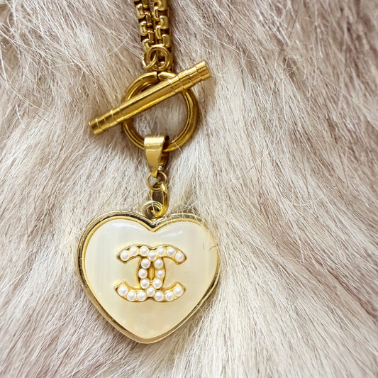 Detalle del botón de marca de lujo recuperado y transformado en collar artesanal ORITIA hecho a mano por EOS UPCYCLING