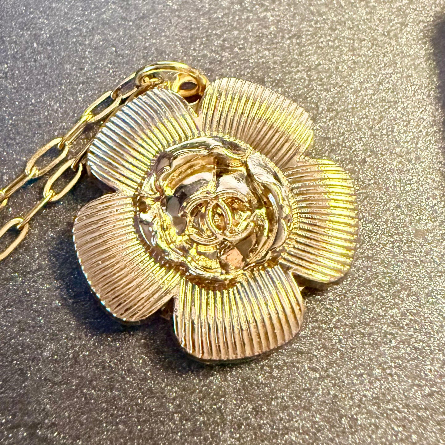 Joya artesanal sostenible con botón CHANEL reciclado en formato de flor.  una segunda vida a piezas con historia a través de un enfoque de upcycling consciente.